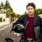 Portrait of confident man sitting on motorcycle. Mature male is holding crash helmet. He is wearing leather jacket on street.